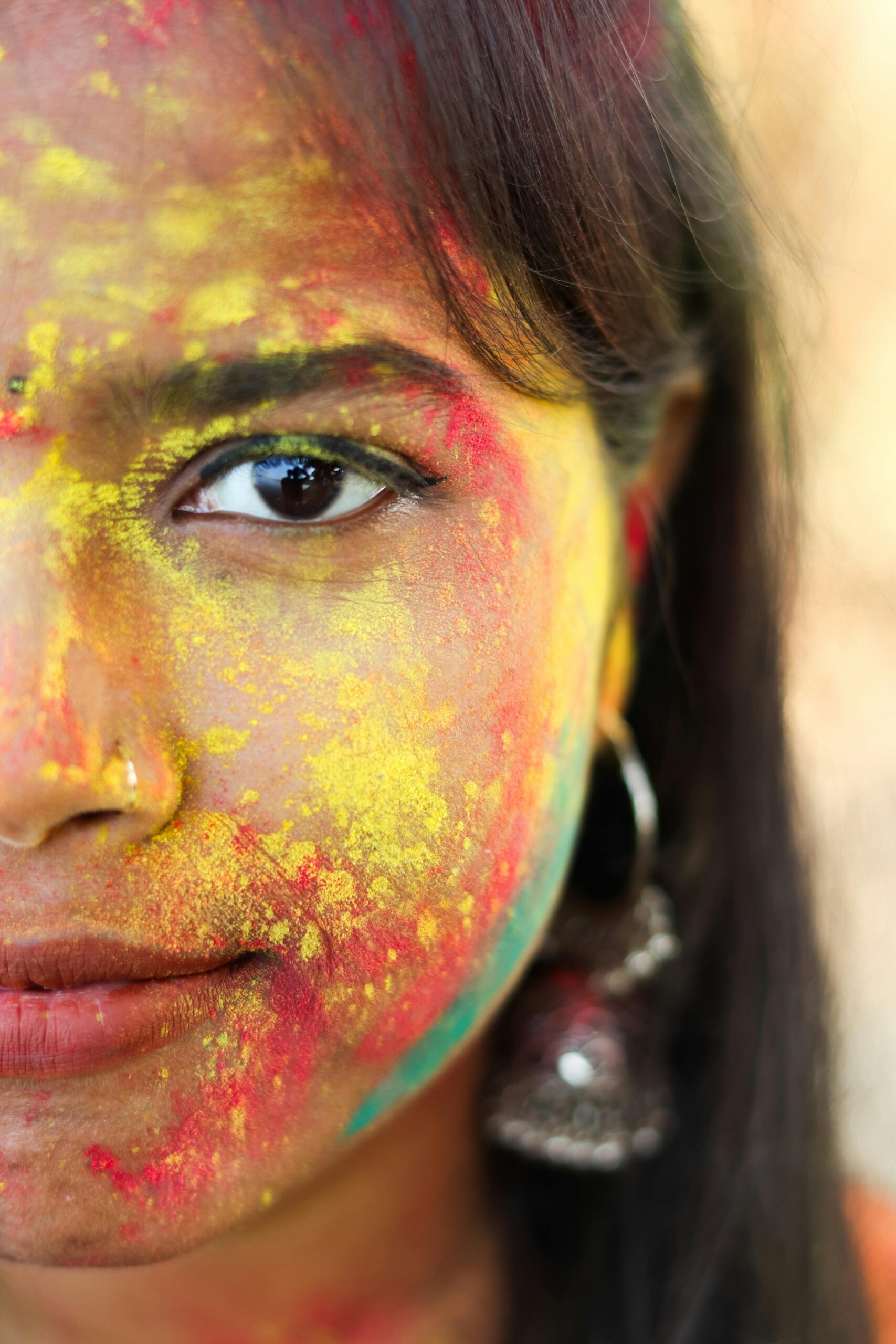 Close-up portrait of a South Asian woman with colorful Holi powder on her face, in Patna, India.